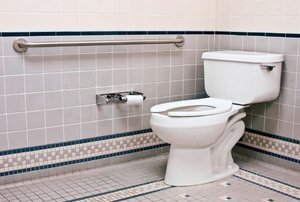 bathroom with toilet, hand rails, and tile