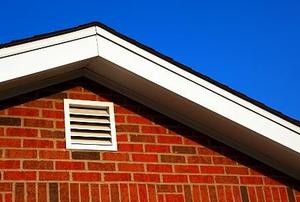 A white gable vent on a brick house.