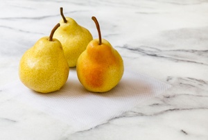 A trio of pears sitting on a marble countertop.