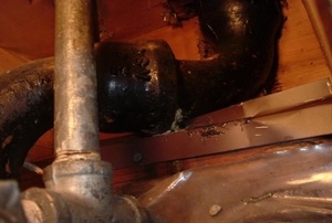 Leaking cast iron drain under a kitchen sink.