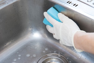 Using a blue sponge to clean a stainless steel sink