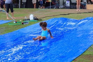 A young girl in a swim suit sliding down a slip 'n slide.
