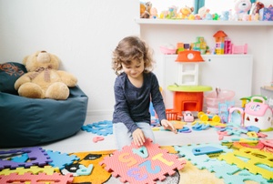 A girl plays on a puzzle mat.