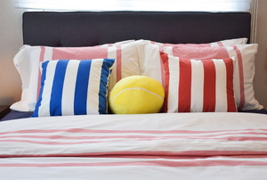 A bed with a dark headboard and striped pillows.