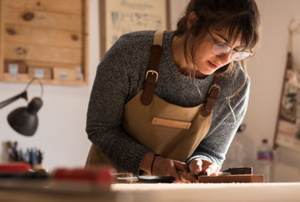woman with glasses and overall woodworking on a table