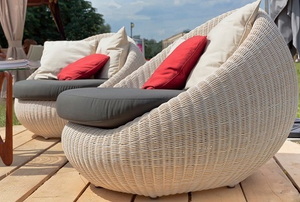 Two large wicker chairs with several cushions on a deck.