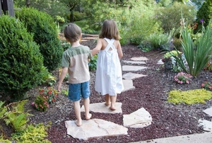 Two kids walk down a garden path.