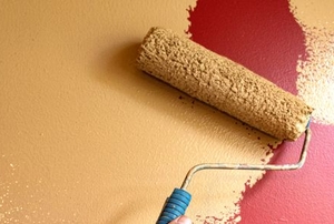 roller painting light tan color over dark red wall