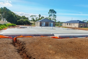 A concrete slab foundation with houses in the background.