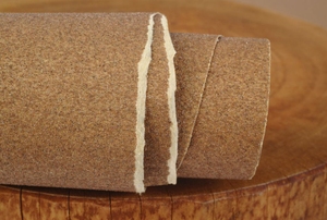 A roll of sandpaper on a wood background.