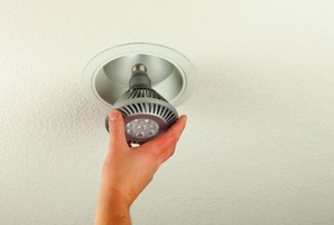 Installing an energy efficient LED light bulb into a ceiling can fixture.