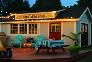 A shed in a backyard with patio furniture and lights.