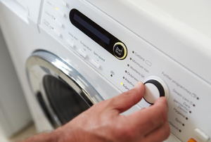 a hand turning a switch on a Washing Machine