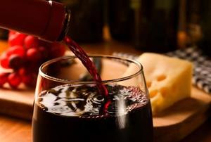 wine pouring into a glass with cheese and grapes in the background