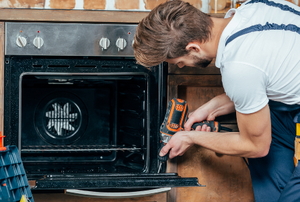 man fixing oven door with screw gun