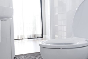A toilet in a bathroom with bright light and white surfaces