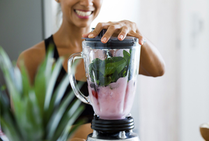 woman making a smoothie in a blender