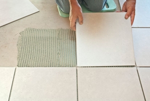 A person laying white bathroom tile.