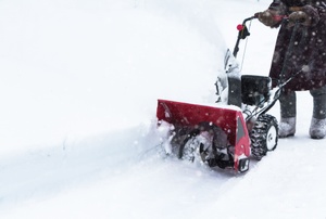 A man pushes a snowblower.