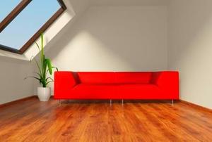Light shining through a skylight onto a red couch in a finished attic.