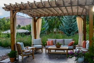 A pergola in the middle of a spacious yard, surrounded by trees.