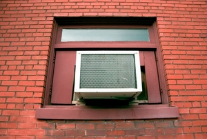 A window air conditioner outside of a brick building.