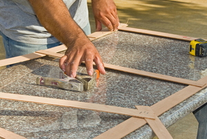 hands measuring frame on granite countertop