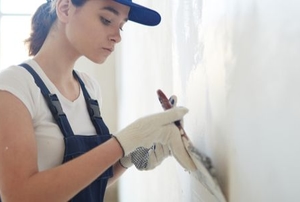 woman applying drywall compound with a wide trowel