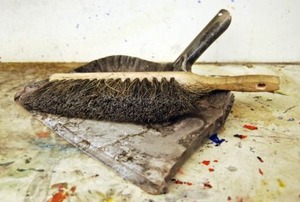 Dirtied linoleum floors with a broom and dustpan sitting on top.
