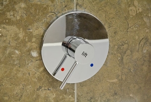 shower handle against a tile shower wall