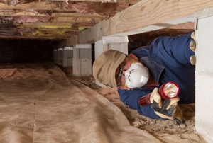 man crawling into a home's crawlspace