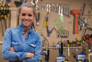HGTV Star Nicole Curtis standing in a workshop with Bernzomatic blow torches. 