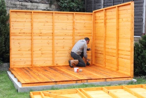A man working on a shed base.