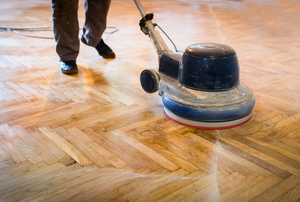 A man waxes parquet floors.