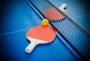 ping pong paddles laying on a table next to the net
