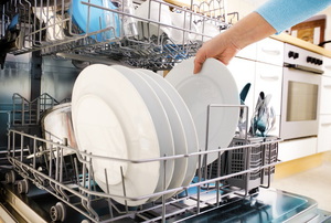 A homeowner unloading clean dishes from their dishwasher.