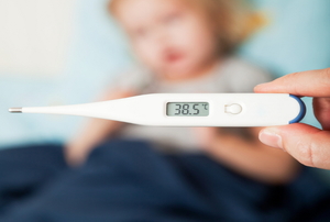 A thermometer in the foreground with a blurry child in the background.