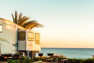 An RV at a beach campsite with the ocean in the background.