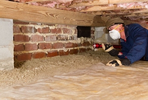 a person in a face mask in a crawl space.