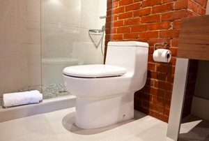 White toilet in a bathroom with a brick wall