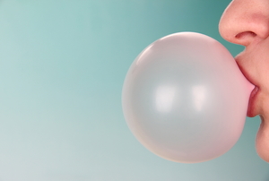 A woman blows a bubble with gum.