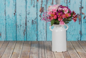 A vase with flowers against a shabby chic blue wall.
