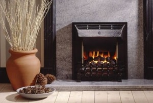 a fireplace with a marble surround, near a display of dry twigs and pinecones