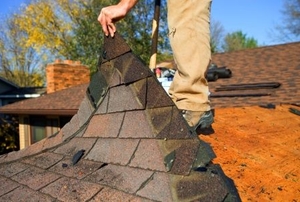 Removing a damaged portion of roof shingles.
