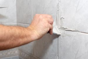 A man works on grout lines.