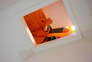 Looking up through an attic hatch at a contractor working.
