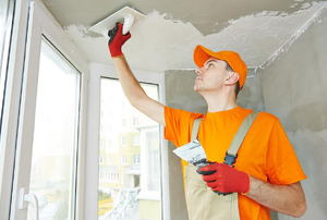 A man applying texture to a ceiling. 