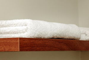 A wood shelf with white towels on it. 