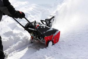 A snow blower being pushed to clear a path.