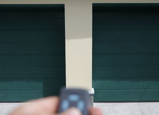 garage door remote pointing at two green garage doors